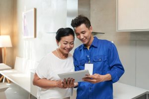 Smiling repairman showing information of tablet computer to senior customer
